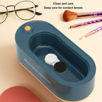 Blue mini contact lens cleaning machine with eyeglasses and makeup brushes on a beige background