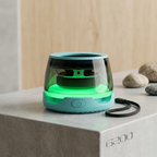 Portable speaker with a green light on a concrete surface